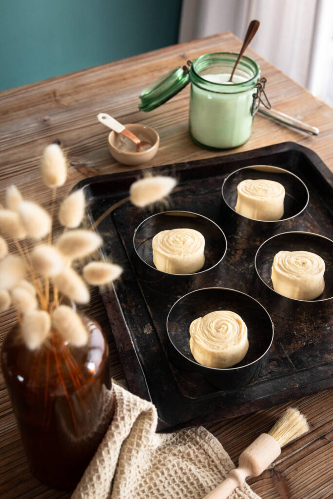 Des ronds de pâte à NY rolls sont en train de pousser sur une place à pâtisserie. Ils sont entourés de cercles à pâtisserie pour des ronds parfaits.